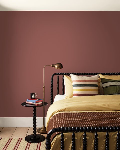 A bedroom with a black bobble frame bed and walls painted in Southwest Pottery 048.