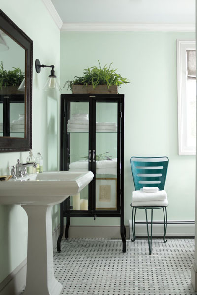 A bathroom with walls painted in Italian Ice Green 2035-70. An accent chair is painted in Teal Ocean 2049-30. The rooms is styled with a black glazed cabinet.