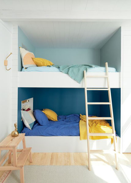 A bunk bed featuring Buxton Blue HC-149 on the upper level and Blue Danube 2062-30 on the lower level. The beds are styled in blue, yellow and teal bedding and cushions.