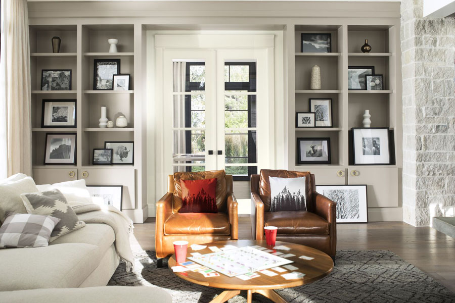 A sumptuous living room with exposed grey bricks and a floor to ceiling shelving unit painted in Silver Fox 2108-50 and Cloud White OC-130.